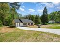 The home is white with a gray roof, a long driveway and green trees in the background of the surrounding property at 157 Fraley Rd, Gastonia, NC 28052