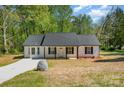 Traditional style, single story home with a black roof, white siding, a covered front porch and a long concrete driveway at 157 Fraley Rd, Gastonia, NC 28052