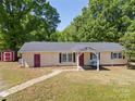 Traditional home boasts a covered porch with swing, red doors, storage shed and well-maintained lawn at 2115 Fowler Secrest Rd, Monroe, NC 28110