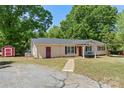 Charming home features a covered porch with swing, red doors, lush lawn and detached storage shed at 2115 Fowler Secrest Rd, Monroe, NC 28110