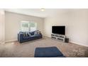 A carpeted living room featuring a sofa with decorative pillows, tv, and neutral paint at 244 Aershire Ct, Concord, NC 28025