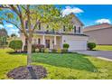 A beautiful two-story home with manicured lawn and mature trees enhancing the curb appeal at 6115 The Meadows Ln, Harrisburg, NC 28075