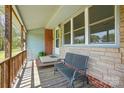 Inviting covered front porch with stone accents, a bench, and a view of the surrounding greenery at 140 Oak Ave, Mount Holly, NC 28120