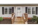 Close-up of the home's entrance with a charming wooden porch, decorative accents, and stylish exterior lighting at 34958 Lowder Rd, New London, NC 28127