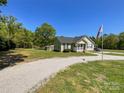 Inviting single-story home on spacious lot with a long gravel driveway and an American flag at 4285 Palmer Lloyd Rd, Lancaster, SC 29720