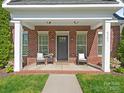 Inviting front porch with brick facade and seating, perfect for enjoying the outdoors at 4303 Patriots Hill Rd, Mint Hill, NC 28227