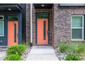 Close-up of a modern brick townhome's vibrant orange front door with sidelight window and landscaping at 648 W End Dr, Charlotte, NC 28208