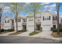 View of townhomes with garages and driveways, surrounded by mature trees and landscaping at 7445 Abigail Glen Dr, Charlotte, NC 28212