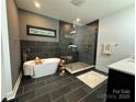 Modern bathroom with a soaking tub, glass-enclosed shower, and sleek black and gray tile work at 12069 Coyle Rd, Stanfield, NC 28163