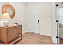 Charming entryway with wood-look floors, a modern cabinet with a round mirror, and a white front door with black hardware at 13752 Roderick Dr # 175, Huntersville, NC 28078