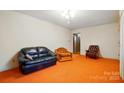 Bright living room with orange carpet featuring comfortable seating and neutral colored walls at 422 Sherrill Farm Rd, Lincolnton, NC 28092