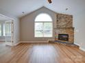 Bright living room features vaulted ceiling, fireplace with stone surround and large window at 4754 Polo Gate Blvd, Charlotte, NC 28216