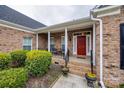 Inviting front porch with classic columns and red door surrounded by lush greenery at 615 Reliance Ct, Tega Cay, SC 29708