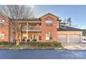 Brick and siding townhome featuring a two-car garage and second story porch at 6512 Quarterbridge Ln, Charlotte, NC 28262
