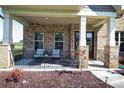 Inviting front porch featuring brick columns, a seating area, and manicured landscaping at 8313 Balcony Bridge Rd, Huntersville, NC 28078