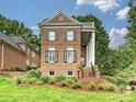 A charming brick home showcasing a symmetrical design, complemented by lush landscaping and mature trees at 8623 Tullamore Park Cir, Charlotte, NC 28226