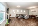 Bright living room with hardwood floors, a fireplace, a gray sectional sofa, and dining area in view at 123 Abersham Dr, Mooresville, NC 28115