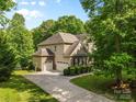 Rear and side view of a home with a long driveway and multiple garage doors, surrounded by mature trees at 1320 Huntcliff Dr, Waxhaw, NC 28173
