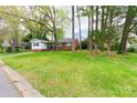 A nice view of the front exterior of the home showing yard, partial driveway, and tree coverage at 1400 Fern Forest Dr, Gastonia, NC 28054