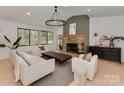 Bright living room with stone fireplace, elegant chandelier, neutral furniture, and large windows at 1437 Jules Ct, Charlotte, NC 28226