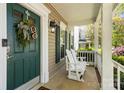Welcoming front porch features white rocking bench and decorative wreath on the door at 18838 Oakhurst Blvd, Cornelius, NC 28031