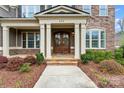Inviting front porch with stone steps, white pillars, and a decorative double front door entrance at 400 Eden Hollow Ln, Weddington, NC 28104