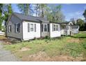 Well-kept single-Gathering house featuring light gray siding and black shutters, surrounded by lush greenery at 6124 Old Plank Rd, Charlotte, NC 28216