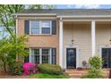 Charming two-story townhome featuring a brick facade, black shutters, and a well-maintained front yard with flowering bushes at 6801 Dumbarton Dr, Charlotte, NC 28210