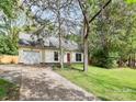 Inviting cream colored home with an attached garage and mature trees in the front lawn at 10432 Camelback Cir, Charlotte, NC 28226