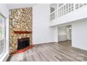 Bright living room with new floors, a stone fireplace, and an open view to the second-floor balcony at 10432 Camelback Cir, Charlotte, NC 28226