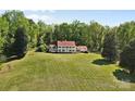 Wide shot of a stately home with a red roof, white exterior, and large lawn surrounded by mature trees at 1233 General Hoke Dr, Lincolnton, NC 28092