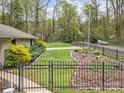 Well-maintained backyard features lush lawn, mature trees, iron fence, and manicured landscaping at 2600 Gemway Dr, Charlotte, NC 28216
