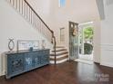 Bright foyer with hardwood floors, staircase, and decorative console table, leading to an open front door at 2751 Collaroy Rd, Waxhaw, NC 28173