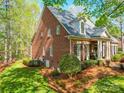 Side view of an elegant brick home surrounded by lush landscaping and mature trees at 3667 Saint Andrews Ln, Gastonia, NC 28056