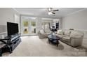 Bright living room with neutral tones, ceiling fan, and french doors to the backyard at 5216 Berkeley View Cir, Charlotte, NC 28277