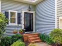 Home's inviting entrance features brick steps and beautiful landscaping with green plants and hanging flower baskets at 6013 Coaching Inn Ct, Charlotte, NC 28270