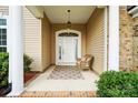 Inviting front porch with a cozy chair, brick accents, and a decorative front door at 7371 Vanguard Ct, Stanley, NC 28164