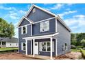 Side view of a two-story house with blue siding, white trim, and lush green surroundings on a partly cloudy day at 2628 S Main St, Kannapolis, NC 28027