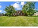 Charming brick home with a well-manicured lawn, mature trees, and tasteful landscaping on a sunny day at 3011 Patrick Place Cir, Clover, SC 29710