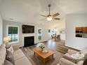 Bright, virtually staged living room features a fireplace, ceiling fan, and open concept design into the dining area at 4147 Timberwood Dr, Gastonia, NC 28056