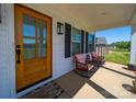 Inviting front porch featuring rocking chairs, a wooden door, and stylish black shutters and lighting at 4189 Brandy Creek Ct, Clover, SC 29710