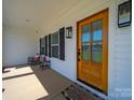 Covered porch boasts rocking chairs, a wood door, stylish light fixtures, and views of the neighborhood at 4189 Brandy Creek Ct, Clover, SC 29710