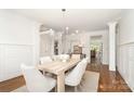Bright dining room with wainscoting, wood floors, modern chandelier, and views to the living areas at 4904 Ardenetti Ct, Mint Hill, NC 28227