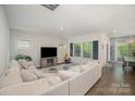 Bright, open living room featuring large windows, hardwood floors, and a comfortable sectional sofa at 7518 Porrera St, Charlotte, NC 28214
