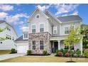 Charming two-story home with stone accents, a well-manicured lawn, and a welcoming front porch for relaxation at 15230 Ravenall Dr, Huntersville, NC 28078