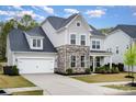 Charming two-story home with stone accents, a well-manicured lawn, and a welcoming front porch for relaxation at 15230 Ravenall Dr, Huntersville, NC 28078