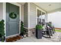 Cozy front porch featuring rocking chairs, potted plants, and a decorative wreath, offering a welcoming entrance at 15230 Ravenall Dr, Huntersville, NC 28078