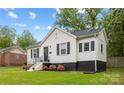 Beautiful home with a white exterior, dark shutters, green lawn and colorful landscaped flower beds at 2414 Remount Rd, Charlotte, NC 28208