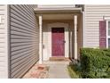 Close-up of the red front door framed by white pillars, complemented by tidy landscaping at 3882 Shasta Cir, Clover, SC 29710