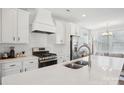 Close-up of a modern kitchen, showing stainless steel appliances, white countertops, and a view into the adjacent living space at 562 Amalfi Dr, Davidson, NC 28036